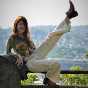 Ismene Schell sitzt auf einer Mauer mit ausgestrecktem Bein vor Stadtpanorama in Stuttgart